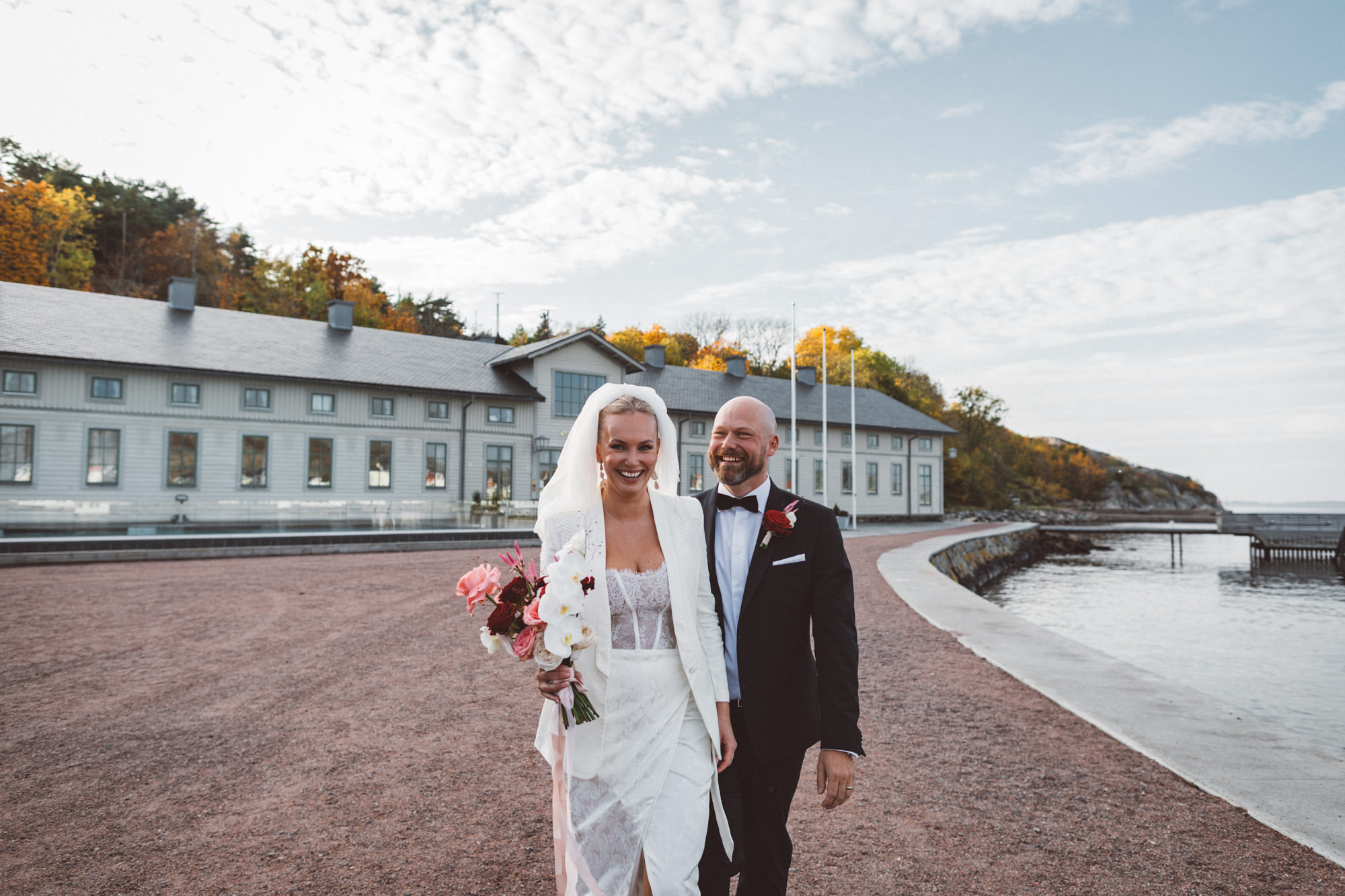 Porträtt av glatt brudpar framför marstrands kurhotell vid havet